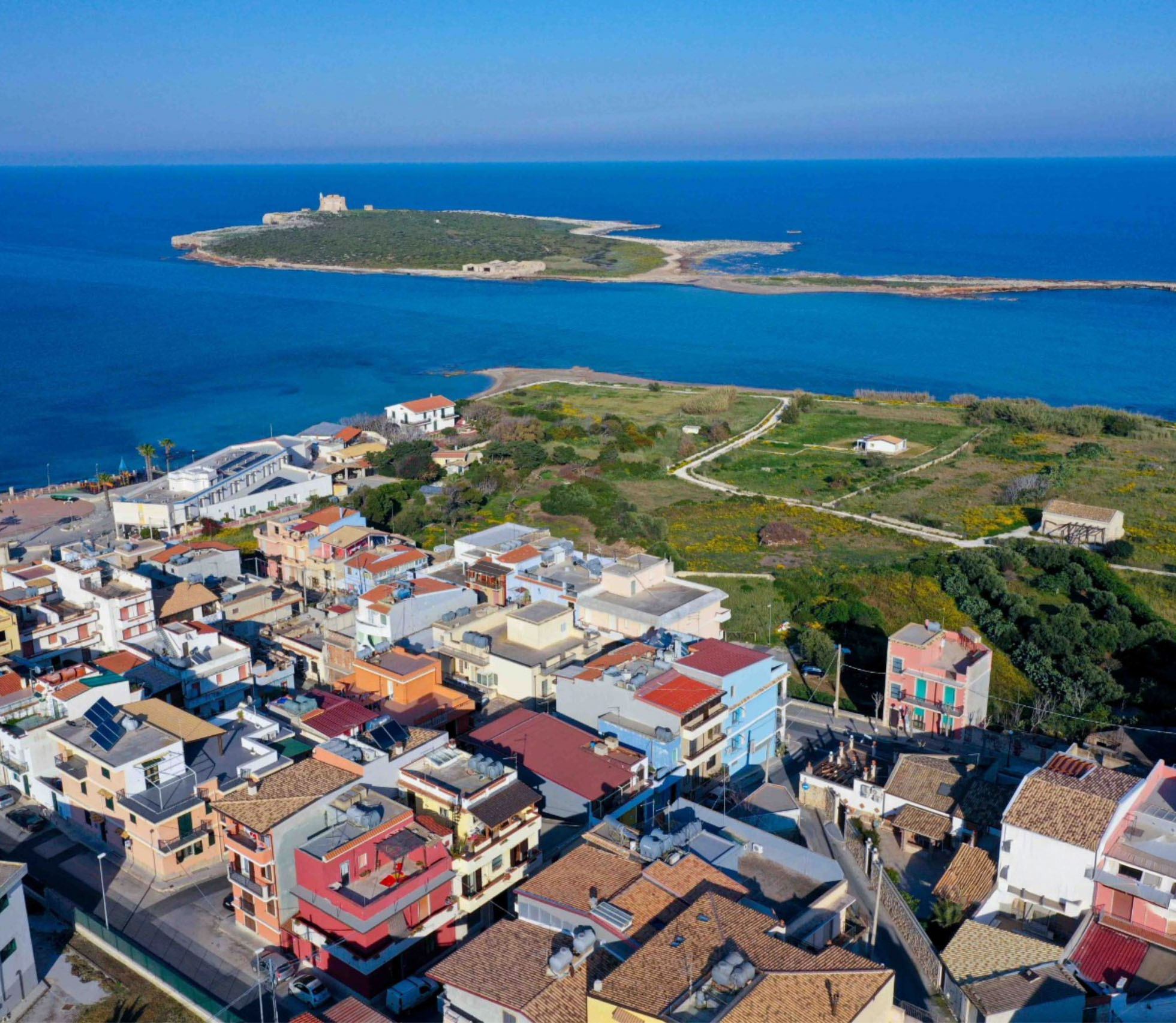 Panoramic aerial view of Portopalo di Capo Passero, with the fishing village on the coast and Isola di Capo Passero bathed in the deep blue sea.