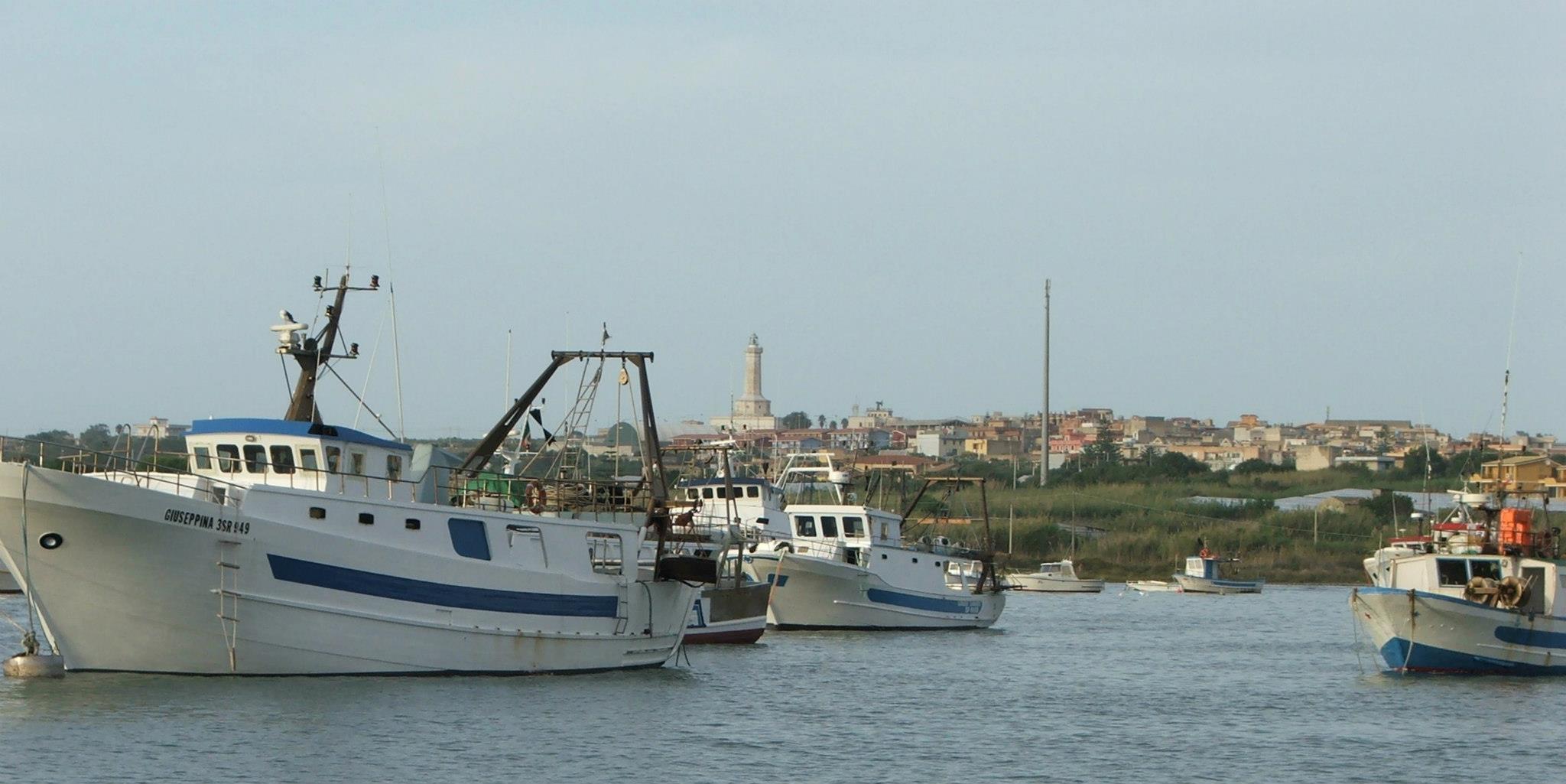 Pescherecci colorati ormeggiati nel porto di Portopalo, pronti per il mercato del pesce.